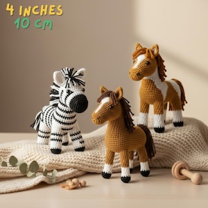 Puede incluir: Tres figuras de animales de ganchillo: una cebra con rayas blancas y negras y dos caballos en tonos marrones y blancos. Cada figura mide aproximadamente 10 cm de altura. Las figuras están hechas a mano y son adecuadas para niños.
