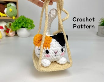 May include: A crocheted cat toy hanging from a beige crocheted swing. The cat is white with orange and black patches. The cat has a cute face with black eyes and a pink nose.