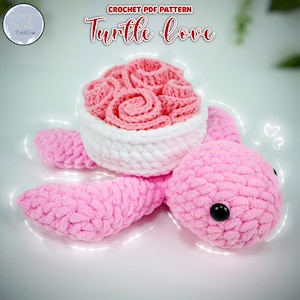 Könnte beinhalten: Eine gehäkelte rosa Schildkröte, die einen gehäkelten Blumenstrauß in Rosa und Weiß hält. Die Schildkröte hat schwarze Augen und eine rosa Schale. Der Text "CROCHET PDF PATTERN Turtle Love" befindet sich oben im Bild.