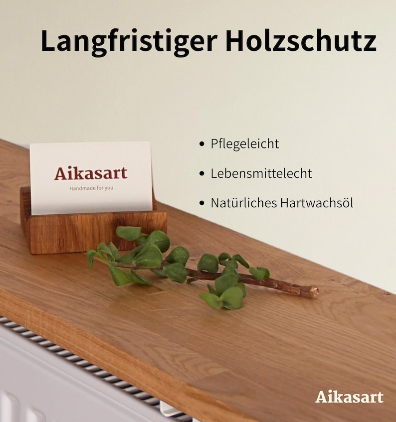 Ein hölzerner Visitenkartenhalter mit einer Karte mit der Aufschrift "Aikasart Handmade for you" steht auf einer Holzoberfläche. Der Text "Langfristiger Holzschutz" steht oben. Ein Zweig mit Grün liegt auf dem Holz.
