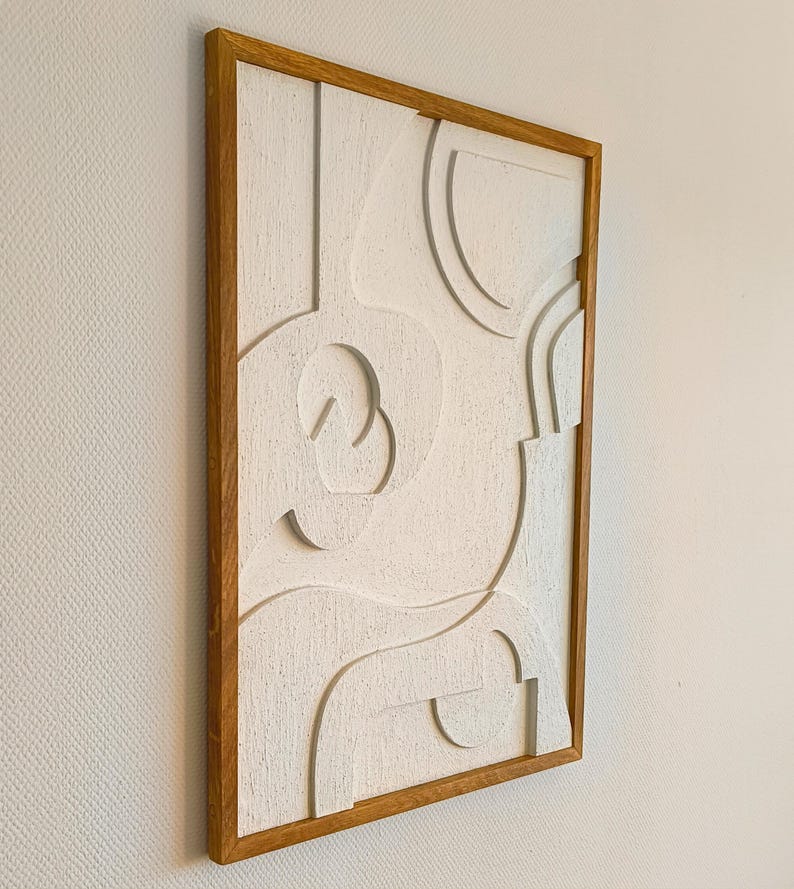 Seitliche Ansicht eines abstrakten 3D Wandreliefs im Format 76 x 56 x 2 cm, gefertigt aus CNC-gefrästem MDF mit strukturierter Oberfläche in natürlichem Cremeweiß. Der hochwertige Rahmen aus massivem, handgeöltem Eichenholz betont das minimalistische Design. Ideal als moderne Wanddekoration für Wohnzimmer, Flur, Büro oder Schlafzimmer im Japandi-, Skandi- oder zeitlosen Stil. Handgefertigte Wandkunst aus natürlichen Materialien.