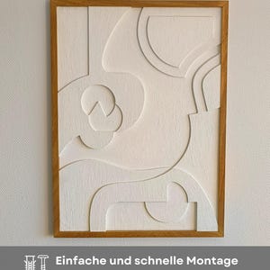 Abstraktes 3D Wandrelief mit geöltem Eichenholzrahmen im Format 76 x 56 x 2 cm, handgefertigt aus gefrästem MDF mit strukturierter Oberfläche in Cremeweiß. Das moderne Wandbild lässt sich dank vormontierter Aufhängung schnell und einfach anbringen – inklusive Schraube und Dübel für sicheren Halt. Ideal als stilvolle Wanddeko für Wohnzimmer, Flur oder Büro im Japandi-, Skandi- oder minimalistischen Stil mit natürlichem Design.