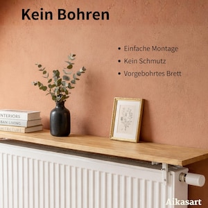 Ein braunes Holzregal von Aikasart hängt über einem weißen Heizkörper an einer weißen Wand. Die Worte "Kein Bohren", "Einfache Montage", "Kein Schmutz" und "Brett vorgebohrt" sind im Bild zu sehen, ebenso der Hinweis "Schraubendreher notwendig!". Das Bild bewirbt ein Wandregal als Floating Shelf, das ohne Bohren montiert werden kann und sich ideal als Deko-Regal über einem Heizkörper eignet. Es betont die einfache Installation.