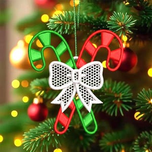 May include: Embroidered Christmas ornament featuring two candy canes in red and green, with a white bow in the center. The ornament is hanging on a Christmas tree with red ornaments and green needles.