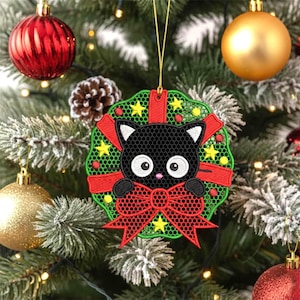 May include: A Christmas tree ornament featuring a black cat with white accents, a red bow, and a green wreath design. The ornament is embroidered with yellow stars and red ribbons. The background includes a Christmas tree with ornaments.
