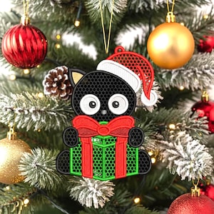 May include: A black cat Christmas ornament wearing a Santa hat and holding a green gift with a red bow. The ornament is hanging on a Christmas tree with red and gold ornaments.