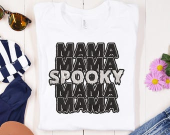 May include: White t-shirt with black text that reads "Mama Mama Spooky Mama Mama" in a dripping font style.