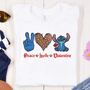 May include: White t-shirt with a blue peace sign, a pink heart with yellow hearts inside, and a blue Stitch character. The text "Peace Love Valentine" is printed below the design.