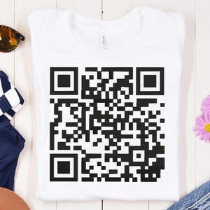 May include: White t-shirt with a black and white QR code printed on the front.