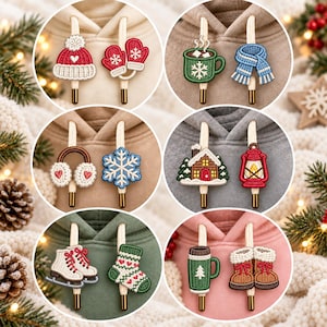 May include: A collection of six circular images displaying various winter-themed hoodie drawstring charms. The charms feature embroidered designs including a red hat, mittens, mugs, a scarf, earmuffs, a snowflake, a house, a lantern, skates, a sock, and boots.
