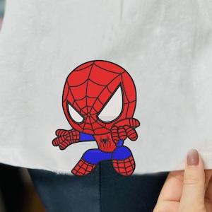 Peut inclure: Une illustration de dessin animé rouge et bleu de Spiderman sur un fond blanc.