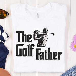May include: White t-shirt with the text "The Golf Father" in bold black letters. A black and white illustration of a golfer swinging a club is featured above the word "Father".