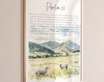 May include: A framed wall art print featuring the text of Psalm 23 in black script and serif font. Below the text is a watercolor illustration of two sheep grazing in a grassy field with rolling mountains and a blue sky in the background.