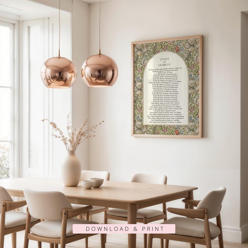 May include: A framed wall art print featuring the Litany of Humility text centred within an arched white panel, surrounded by a dense botanical pattern of green leaves and multi-coloured flowers, displayed in a light-toned wooden frame.