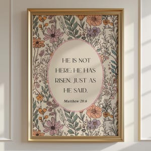 May include: A framed print with a gold frame features floral artwork in pastel colors. The text "HE IS NOT HERE: HE HAS RISEN. JUST AS HE SAID. Matthew 28:6" is centered within an oval shape.