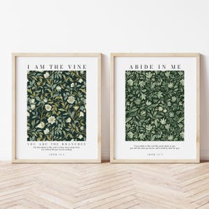 May include: Two framed wall art prints with light wood frames. The left print features a dark green floral pattern with the text I AM THE VINE YOU ARE THE BRANCHES JOHN 15:5. The right print shows a green botanical pattern with ABIDE IN ME JOHN 15:7.