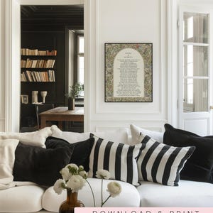May include: A framed wall art print featuring the text Litany of Humility surrounded by a colourful floral and botanical border. The print is displayed on a white wall above a white sofa with black and white striped and solid black throw pillows.