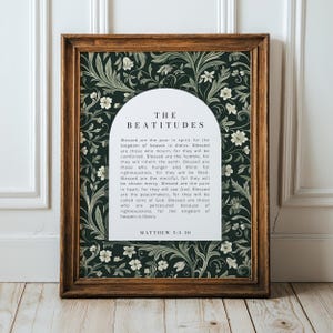 May include: A framed print featuring the text "THE BEATITUDES" in a decorative font. The print has a dark green floral background and a wooden frame. The text from Matthew 5:3-10 is also included.