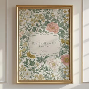 May include: A framed floral print featuring a cream-colored background with a pattern of flowers in shades of pink, white, and yellow, and green leaves. The print includes the text "Be still, and know that I am God." in a decorative frame.