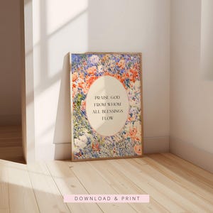May include: A rectangular framed wall art print featuring a vibrant impressionist-style floral meadow in shades of blue, orange, and white. A central cream-colored oval contains the black text: PRAISE GOD FROM WHOM ALL BLESSINGS FLOW.