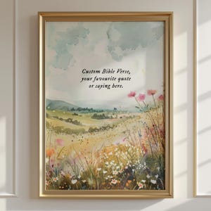 May include: A framed wall art print featuring a watercolor landscape of rolling hills and a wildflower meadow. The text "Custom Bible Verse, your favourite quote or saying here." is centered in the upper portion against a soft blue sky.