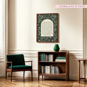 May include: A framed print featuring the "Prayer of St. Francis" with a dark green floral design. The print hangs above a wooden bookshelf filled with books and a green vase. A green armchair and a small side table are also visible.