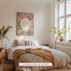 May include: A rectangular wall art print in a thin frame featuring a vibrant floral border of blue, orange, and pink flowers surrounding a central cream oval with the black text: PRAISE GOD FROM WHOM ALL BLESSINGS FLOW. The print is displayed above a bed.
