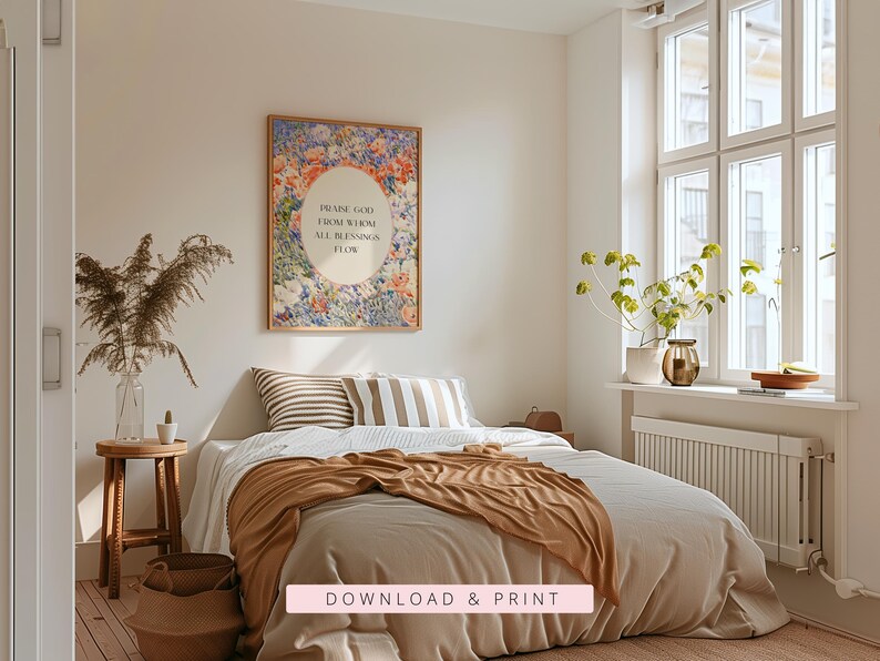 May include: A rectangular wall art print in a thin frame featuring a vibrant floral border of blue, orange, and pink flowers surrounding a central cream oval with the black text: PRAISE GOD FROM WHOM ALL BLESSINGS FLOW. The print is displayed above a bed.