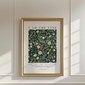 May include: A framed art print with a gold frame. The print features a dark green floral pattern with white and yellow flowers. The text "I AM THE VINE" is at the top, and "YOU ARE THE BRANCHES" and a Bible verse are at the bottom.