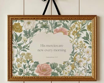 May include: A rectangular wall art piece in an ornate gold frame with a black ribbon hanger. The print features a botanical pattern of pink and white flowers with green leaves and gold accents, surrounding a central cream label with the text: His mercies are new every morning, Lamentations 3:23.