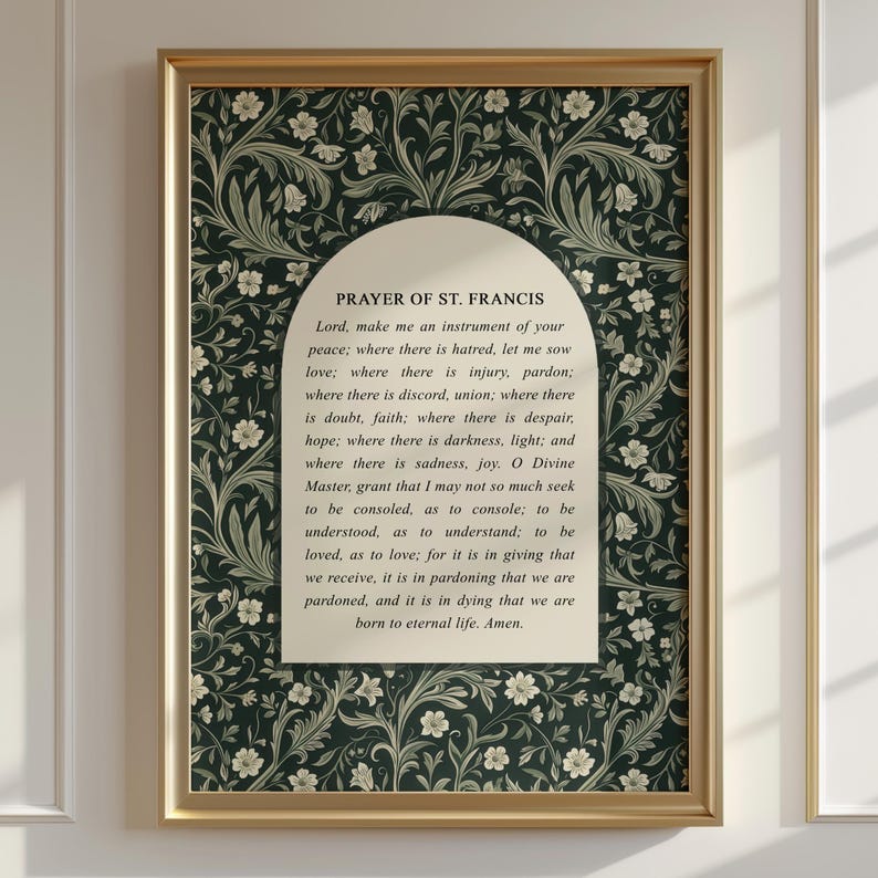 May include: A framed print featuring the "Prayer of St. Francis" text. The print has a gold frame and a dark green floral patterned background. The text is in a cream-colored arch shape in the center of the print.