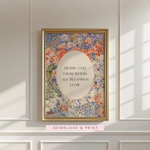 May include: A framed wall art print featuring a watercolor-style floral meadow in shades of orange, blue, and green. A central cream-colored oval contains the black text: PRAISE GOD FROM WHOM ALL BLESSINGS FLOW. The frame is a metallic gold finish.