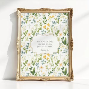 May include: A framed print with a gold ornate frame. The print features a floral pattern with yellow, blue, and white flowers and green leaves. A white, cloud-shaped text box contains the words "HE IS NOT HERE; HE HAS RISEN, JUST AS HE SAID. Matthew 28:6."