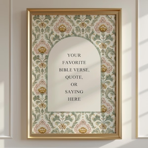 May include: A framed print with a gold-colored frame. The print features a floral pattern in pink, green, and gold. The center has an arched shape with the text: "YOUR FAVORITE BIBLE VERSE, QUOTE, OR SAYING HERE."