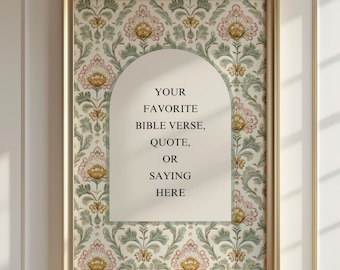 May include: A rectangular wall art piece in a gold frame featuring a cream-colored arch in the center with the text YOUR FAVORITE BIBLE VERSE, QUOTE, OR SAYING HERE. The background displays a repeating floral pattern in shades of pink, green, and gold.