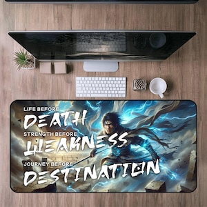May include: A rectangular desk mat with a fantasy warrior illustration and blue lightning. The mat displays the text "LIFE BEFORE DEATH", "STRENGTH BEFORE WEAKNESS", and "JOURNEY BEFORE DESTINATION". A computer, keyboard, and other desk accessories are visible on a wooden desk.