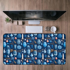 May include: A rectangular desk mat with a dark blue background and a repeating pattern of fantasy-themed objects. The pattern includes swords, potions, shields, and other game-related items in shades of blue, brown, and orange.