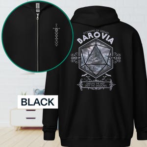 Puede incluir: Sudadera con capucha negra con cremallera y un gráfico blanco en la espalda con el texto "DOMAINS OF DREAD BAROVIA" y un diseño de dado D20 con una escena de castillo. La parte delantera tiene un pequeño diseño de espada blanca. La palabra "BLACK" está en la parte inferior.