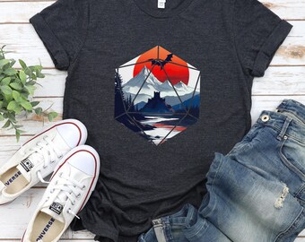 May include: A dark gray t-shirt with a graphic of a mountain range, a castle, and a dragon flying over a red sun, all inside a geometric shape resembling a twenty-sided die.