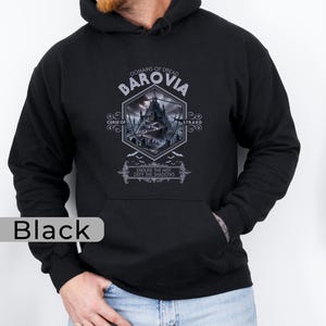 Op de afbeelding: Zwart hoodie met een grafische print van een gotisch kasteel en de tekst "Domains of Dread Barovia Curse of Strahd Endure the Mist Defy the Shadows".