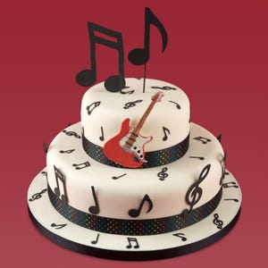 Può includere: Una torta bianca a due piani decorata con sagome di note musicali nere e un topper a forma di chitarra elettrica rossa. La base di ogni piano presenta un nastro scuro con un sottile motivo a pois multicolore e grandi note nere in cima.
