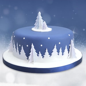 Op de afbeelding: Een blauwe met fondant bedekte cake versierd met witte fondantbomen en witte stippen. De cake staat op een witte cakeplaat met een blauw lint om de onderkant.