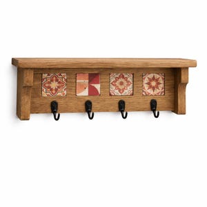 May include: Wooden wall-mounted shelf with four black hooks. The shelf features four decorative square tiles with floral and geometric patterns in red, orange, and cream colors. The shelf is made of light brown wood.