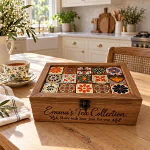 May include: A rectangular wooden tea box with a hinged lid featuring a grid of fifteen colorful floral and geometric patterned tiles. The front of the box is engraved with the text Emma's Tea Collection Made with love, just for you.