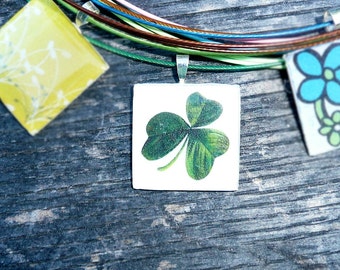 Trebol - Silver square resin pendant on a dark green wire.