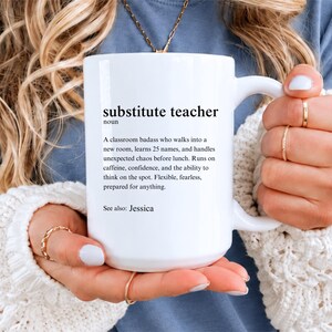 May include: A white ceramic mug featuring black printed text that defines the term substitute teacher as a classroom badass who handles unexpected chaos, runs on caffeine, and is prepared for anything, with the final line reading See also: Jessica.