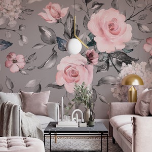 May include: A living room interior with a gray wall featuring a floral wallpaper with pink roses and gray leaves. The room is decorated with a gray couch, a pink armchair, a coffee table, and a gold lamp.