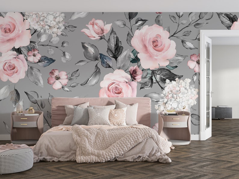 May include: A bedroom with a gray floral wallpaper featuring pink roses and gray leaves. The bed is made with a pink blanket and pillows. There are two nightstands with lamps on either side of the bed.