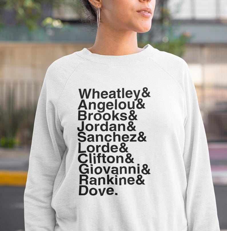 May include: White sweatshirt with black text listing names: Wheatley, Angelou, Brooks, Jordan, Sanchez, Lorde, Clifton, Giovanni, Rankine, and Dove. The sweatshirt is a crew neck style.