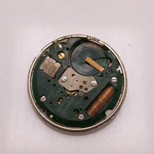 May include: A disassembled watch movement with a green circuit board and metallic components. The watch movement has a silver metal casing. The text "SEIKO 7506A SPR" is visible on the circuit board.